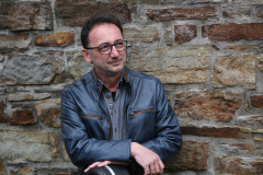 Lutz Scheufler gestützt auf Gitarrenkoffer für Natursteinwand